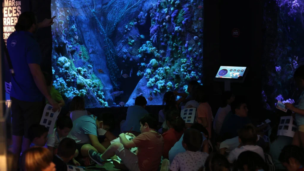Niña junto a un guía en una actividad educativa en el acuario